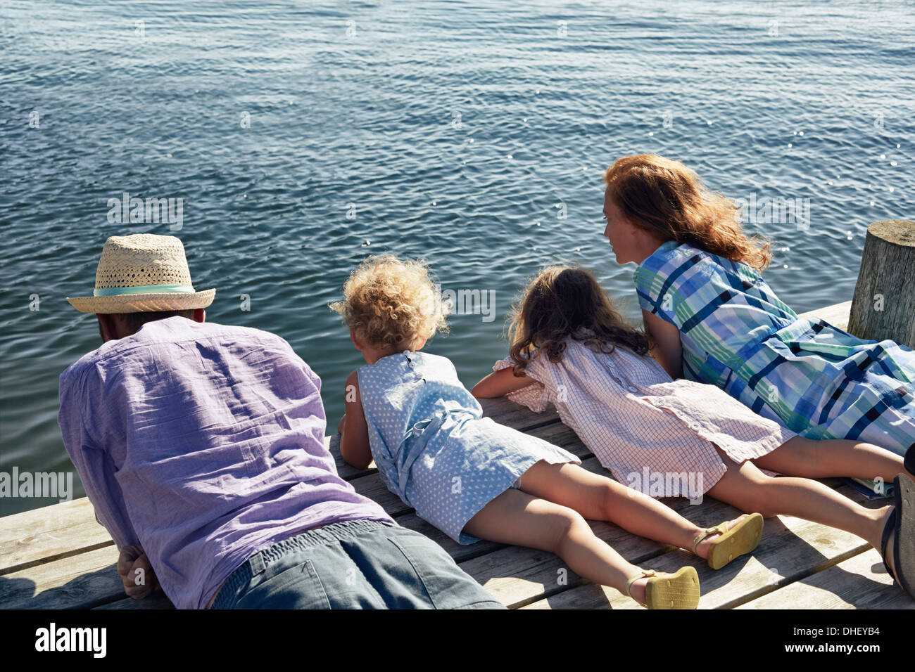Parents and daughters lying on pier, Utvalnas, Gavle, Sweden Stock Photo