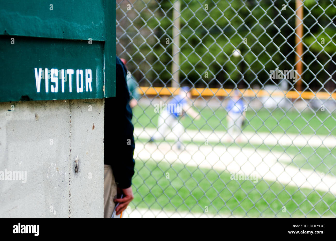 A baseball coach watches a youth baseball game from the visitor's dugout Stock Photo Alamy