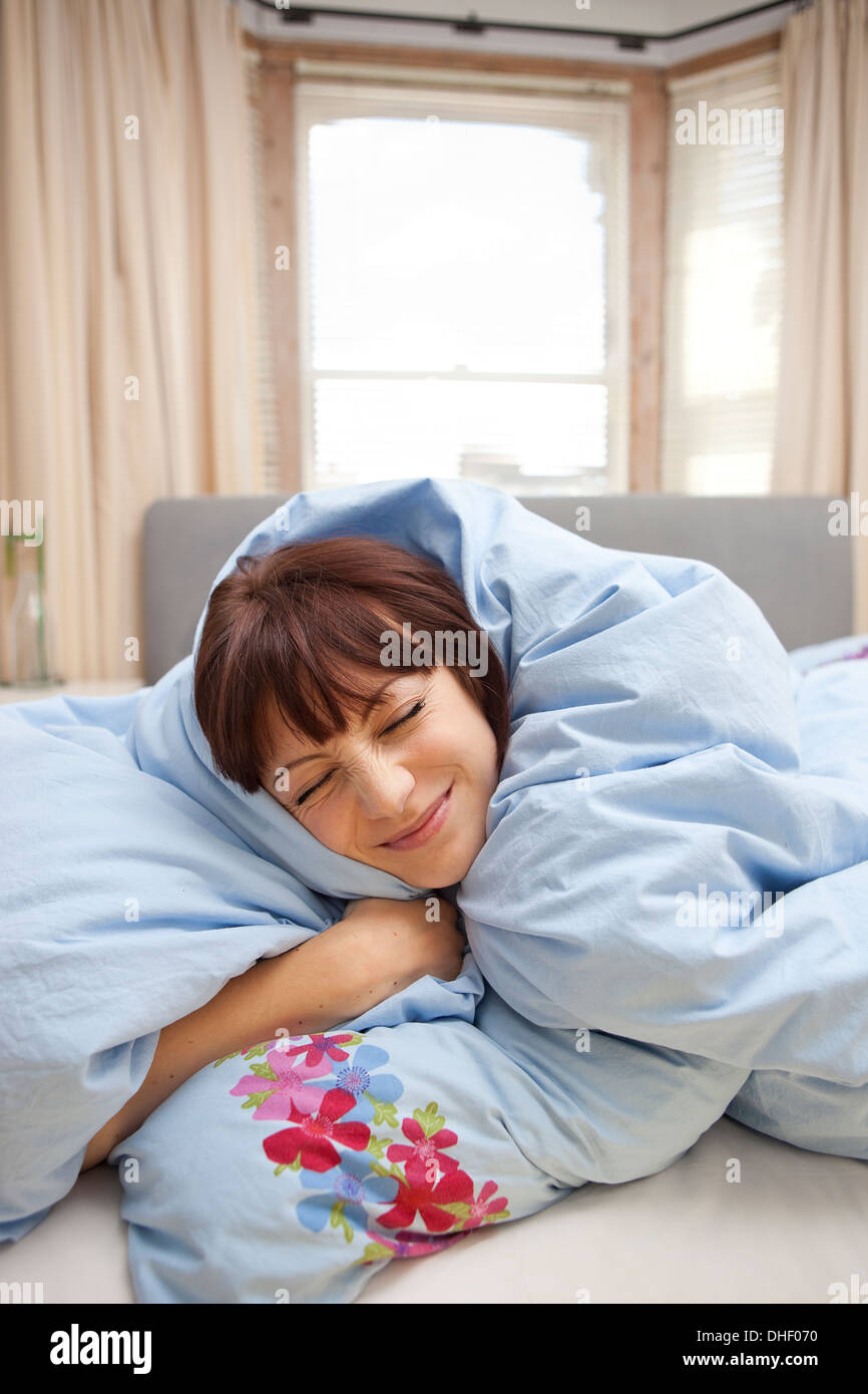 Young woman wrapped in duvet Stock Photo