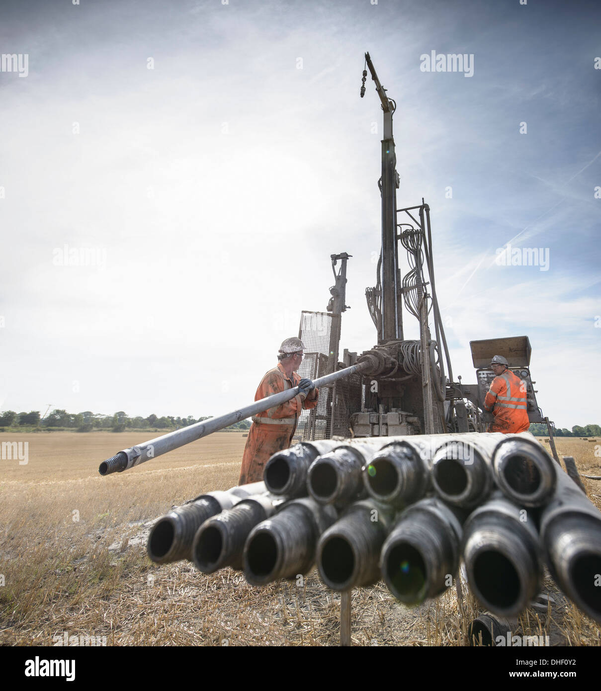 Workers operating drilling rig in field Stock Photo