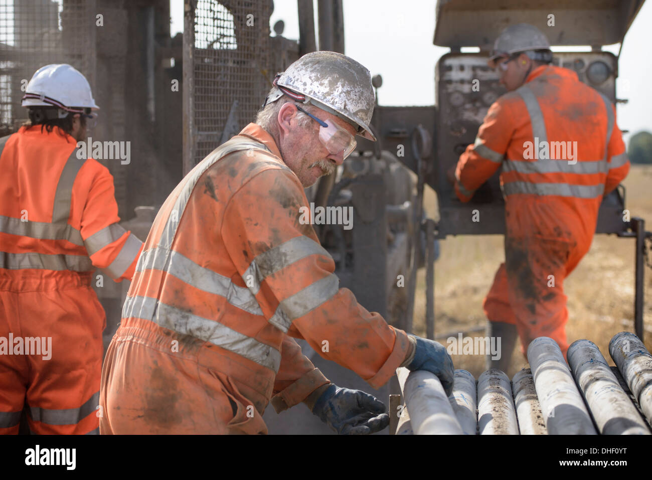 Workers in hard hats operating drilling rig Stock Photo