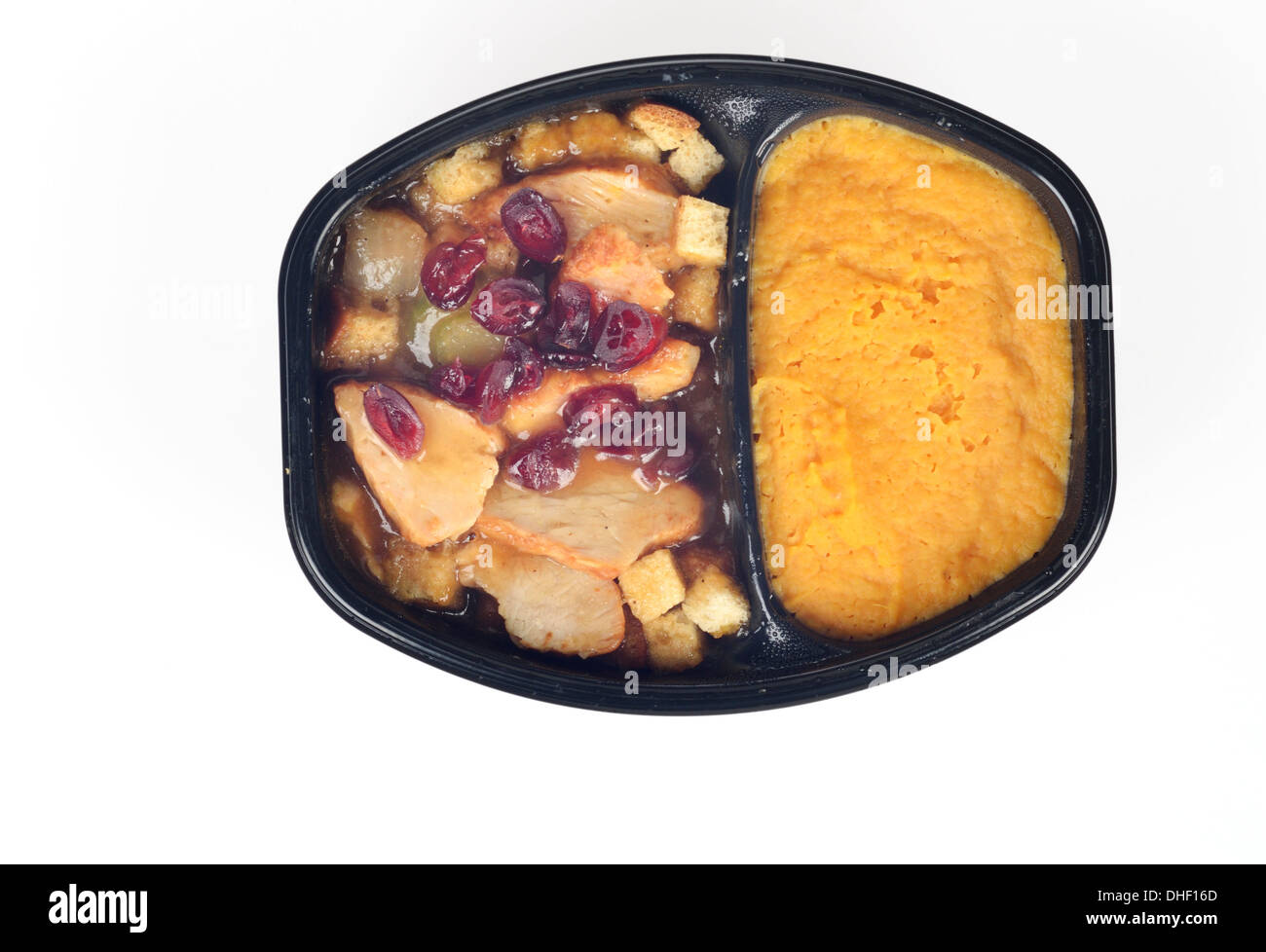 Microwave cooked hot tv dinner of turkey, stuffing, cranberries and gravy with butternut squash isolated on white background Stock Photo
