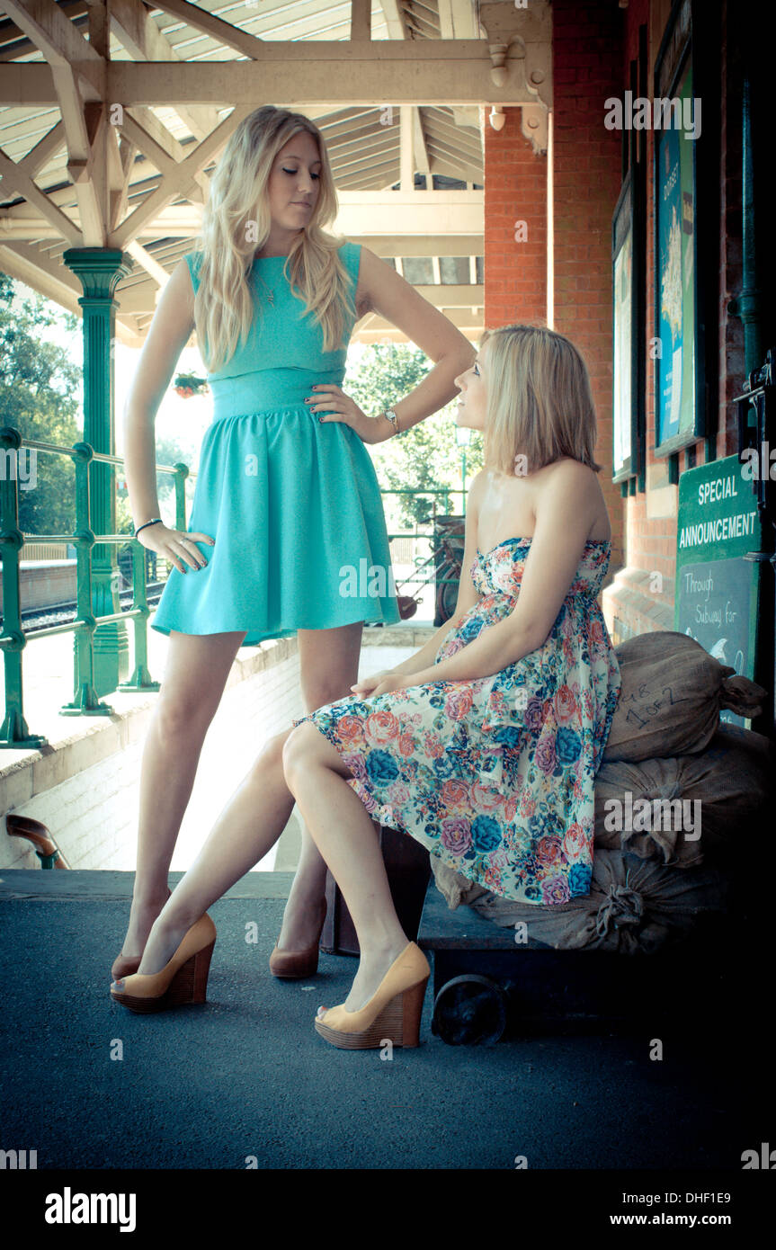Young pretty blond girls waiting at a vintage railway station Stock Photo