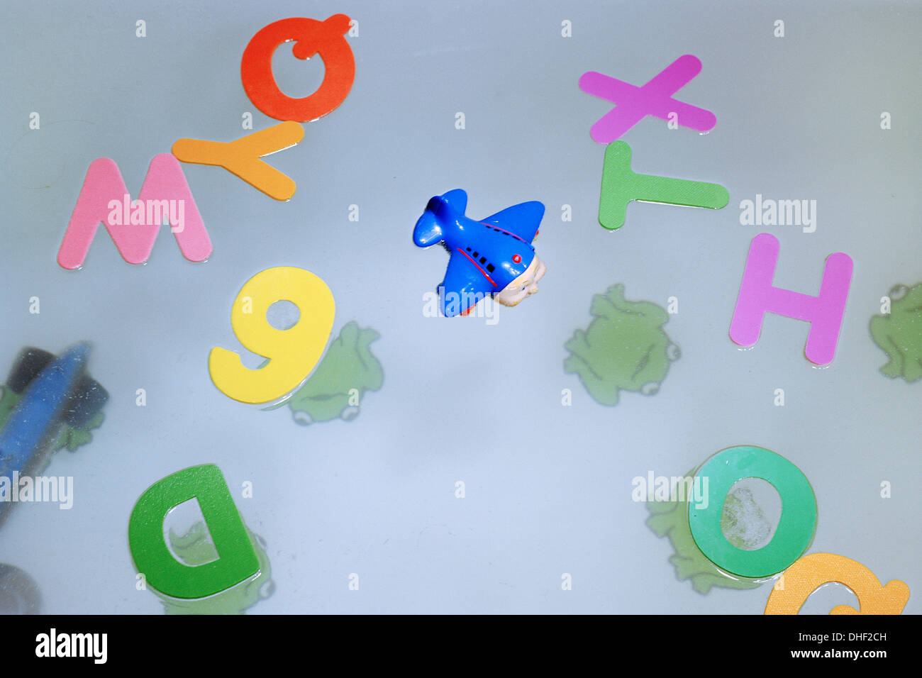 Toy airplane floats in a bathtub with letters from the alphabet Stock Photo