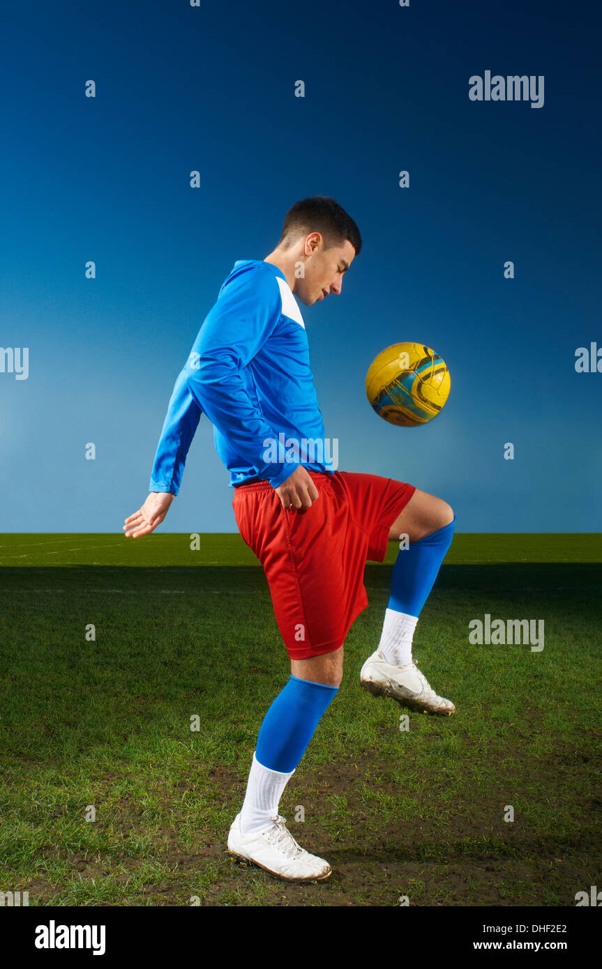 Young man playing keepy uppy with football Stock Photo
