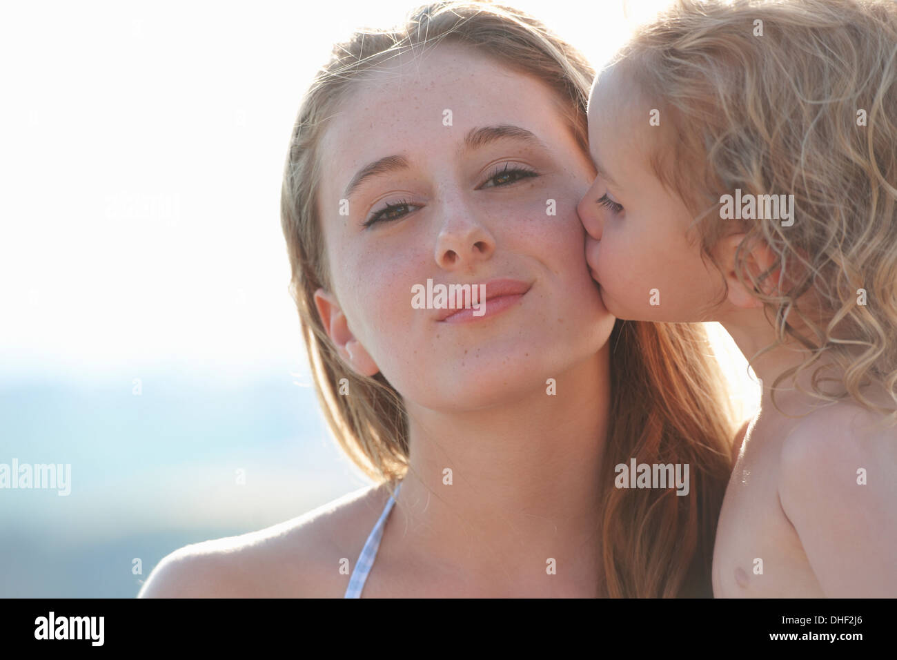 Portrait of young girl kissing older sister Stock Photo