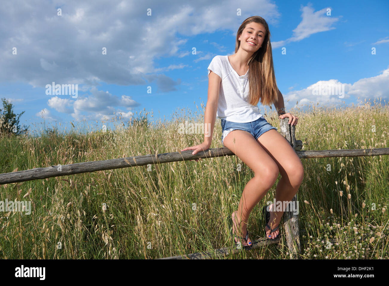 Teenage girl sitting on wooden fence, Tuscany, Italy Stock Photo