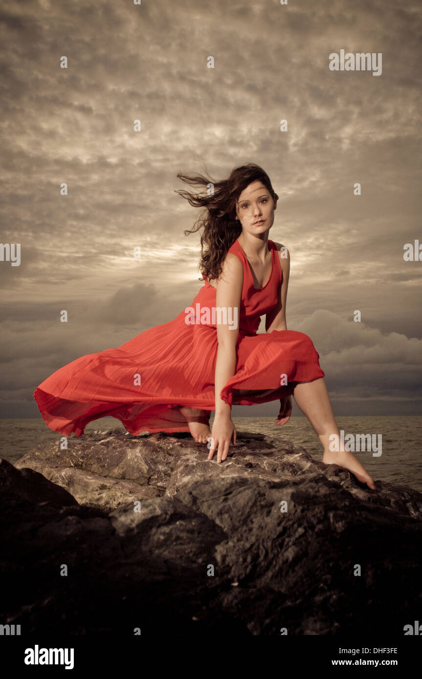 Brunette model on rocky beach during a storm Stock Photo
