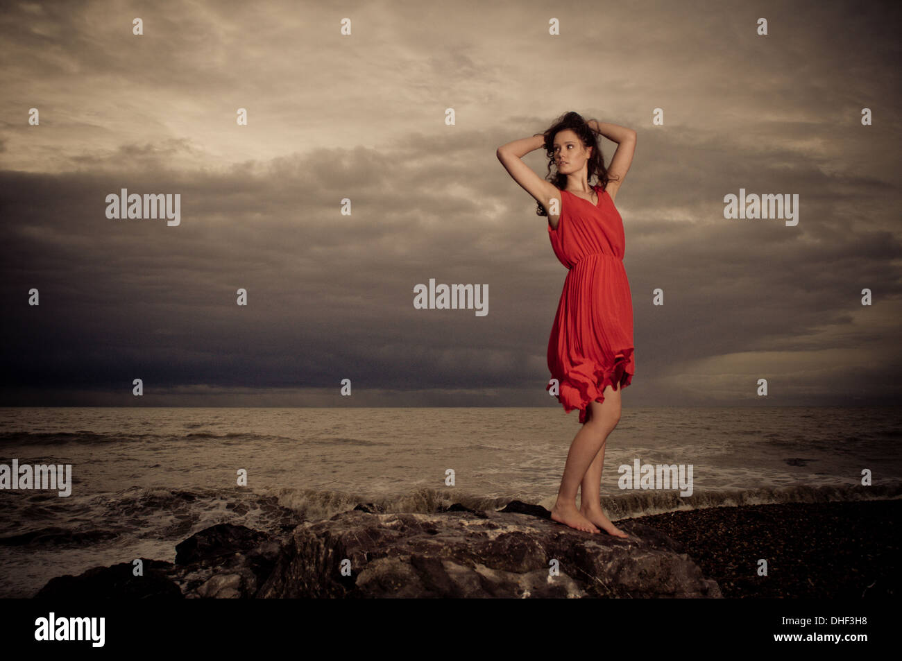 Brunette model on rocky beach during a storm Stock Photo