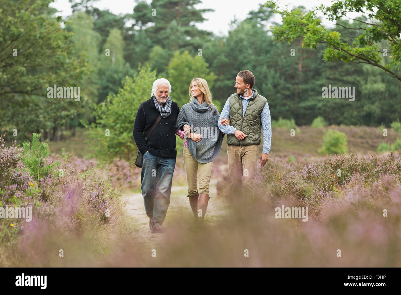 Senior man, mid adult man and woman walking through forest Stock Photo