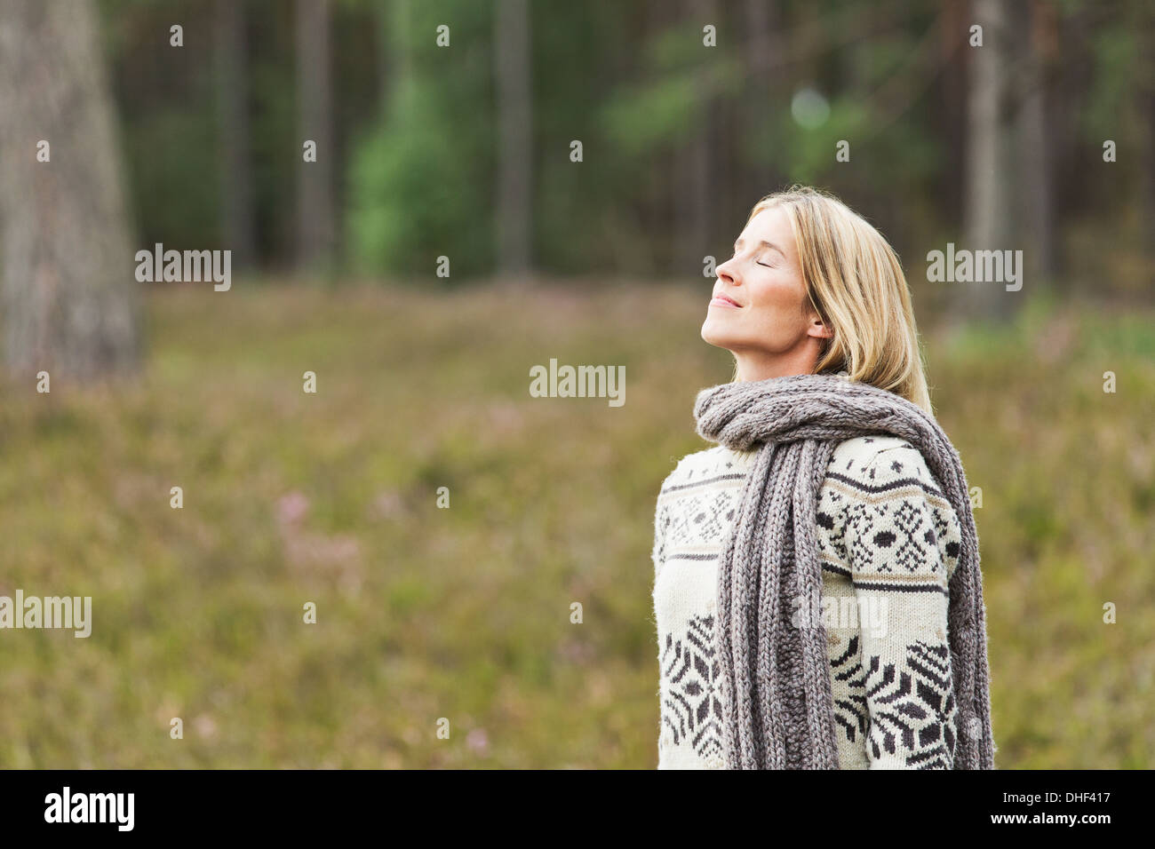 Mid adult woman wearing sweater with eyes closed Stock Photo