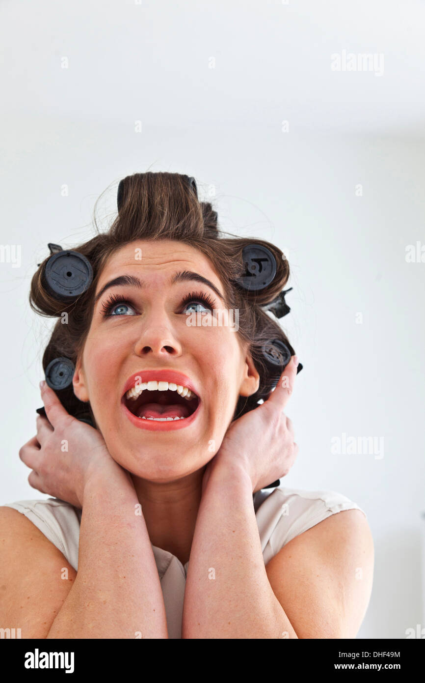 Young woman wearing hair rollers looking up Stock Photo
