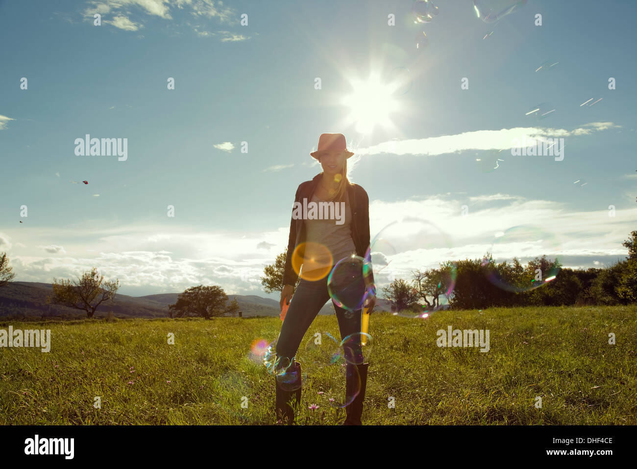 Young woman in field with blown bubbles Stock Photo