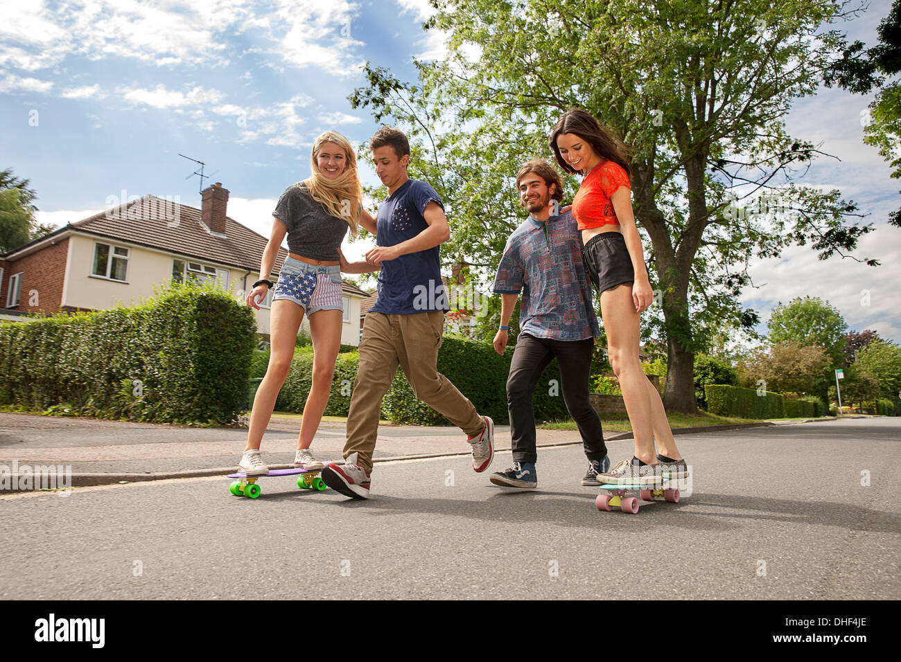 Two young couples skateboarding on road Stock Photo