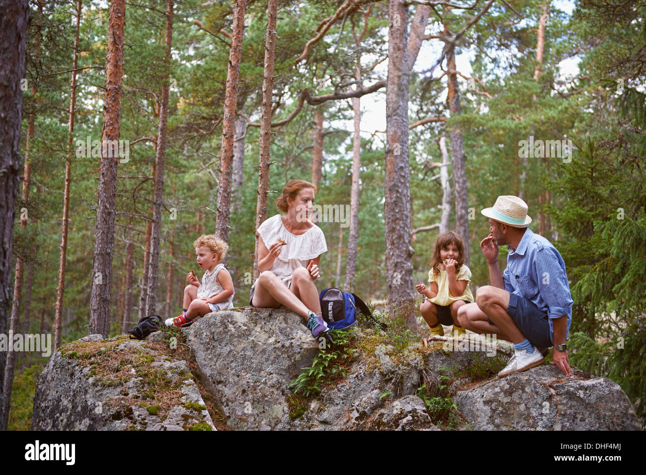 Family sitting on rocks in forest eating picnic Stock Photo