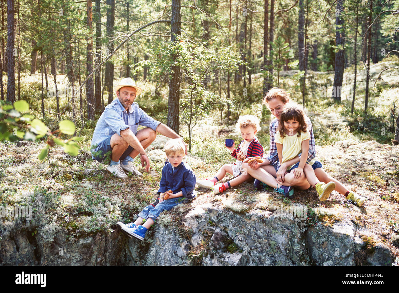 Family sitting on rocks in forest Stock Photo
