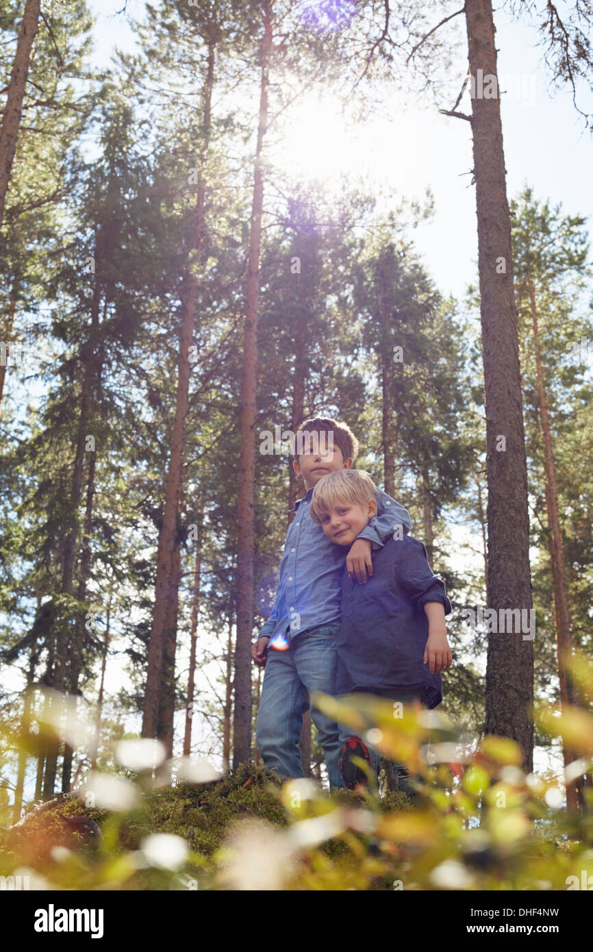 Brothers standing in forest with arm around Stock Photo