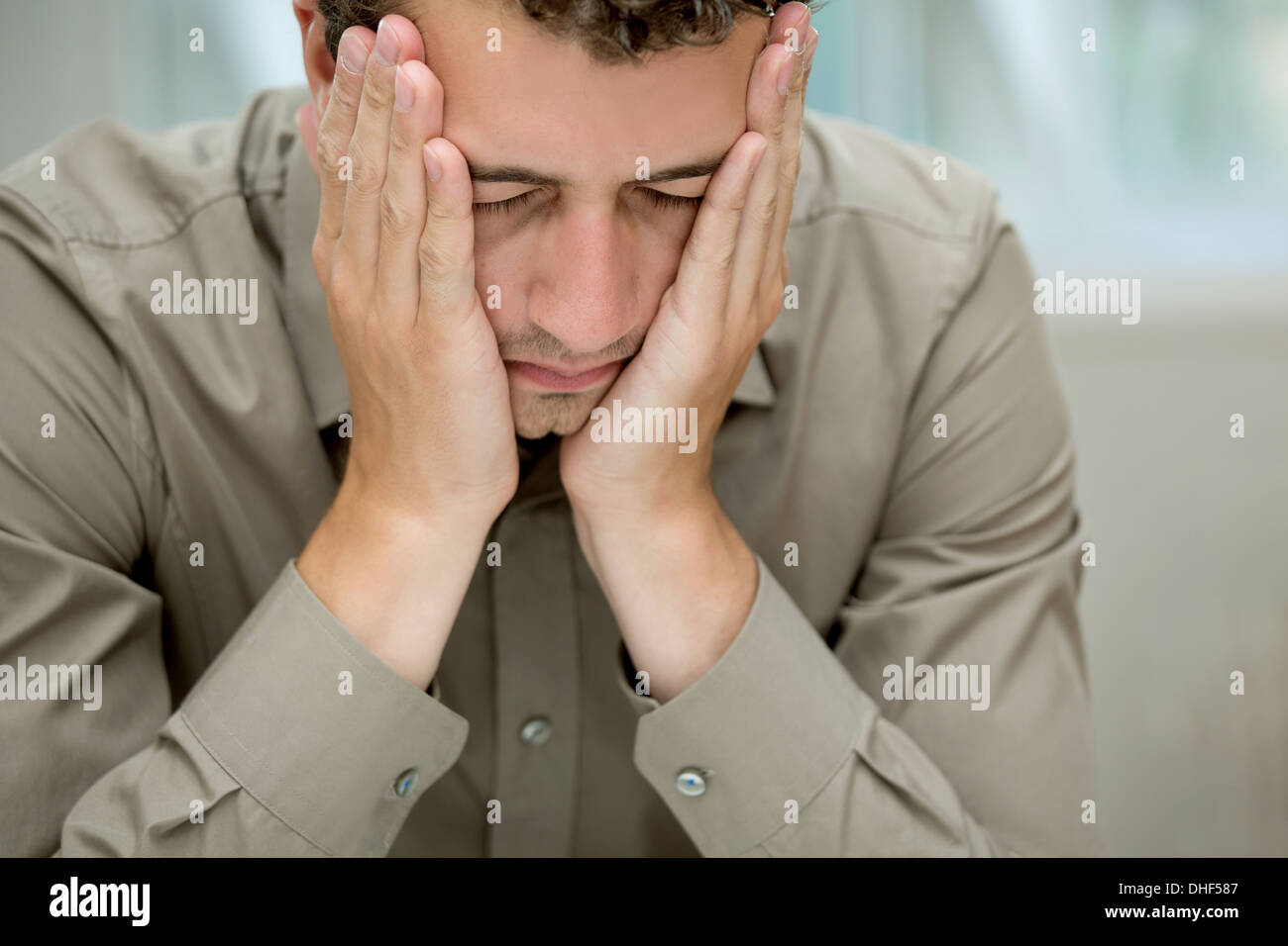 Young man covering cheeks with hands Stock Photo