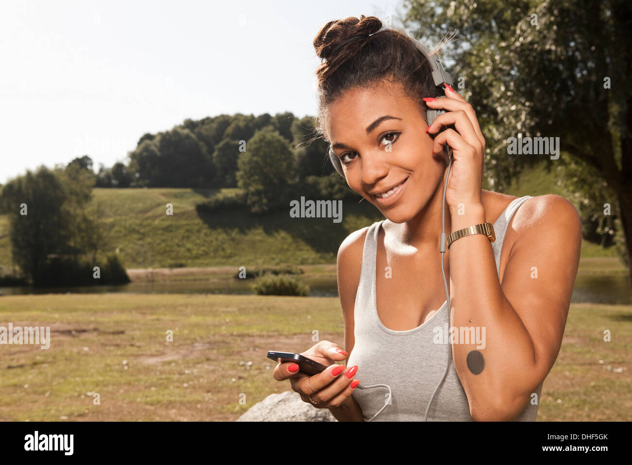 Young woman listening to mp3 player in park Stock Photo