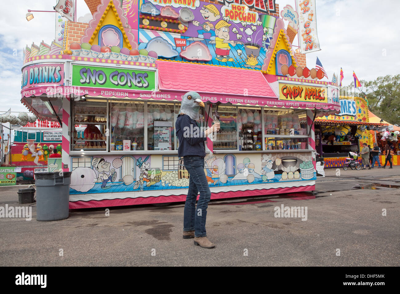 woman wearing a pigeon mask holds a turkey leg at the state fair. Stock Photo