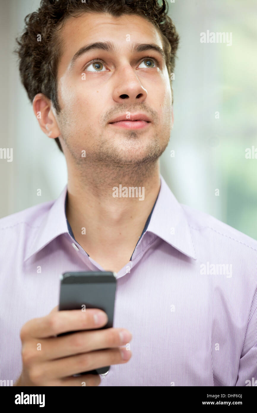 Young man looking up from mobile phone Stock Photo