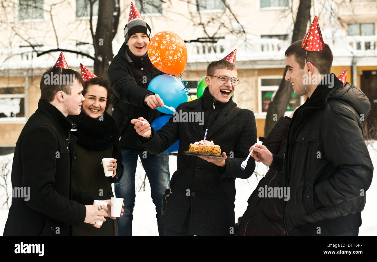 Group of young friends on city street with birthday cake Stock Photo
