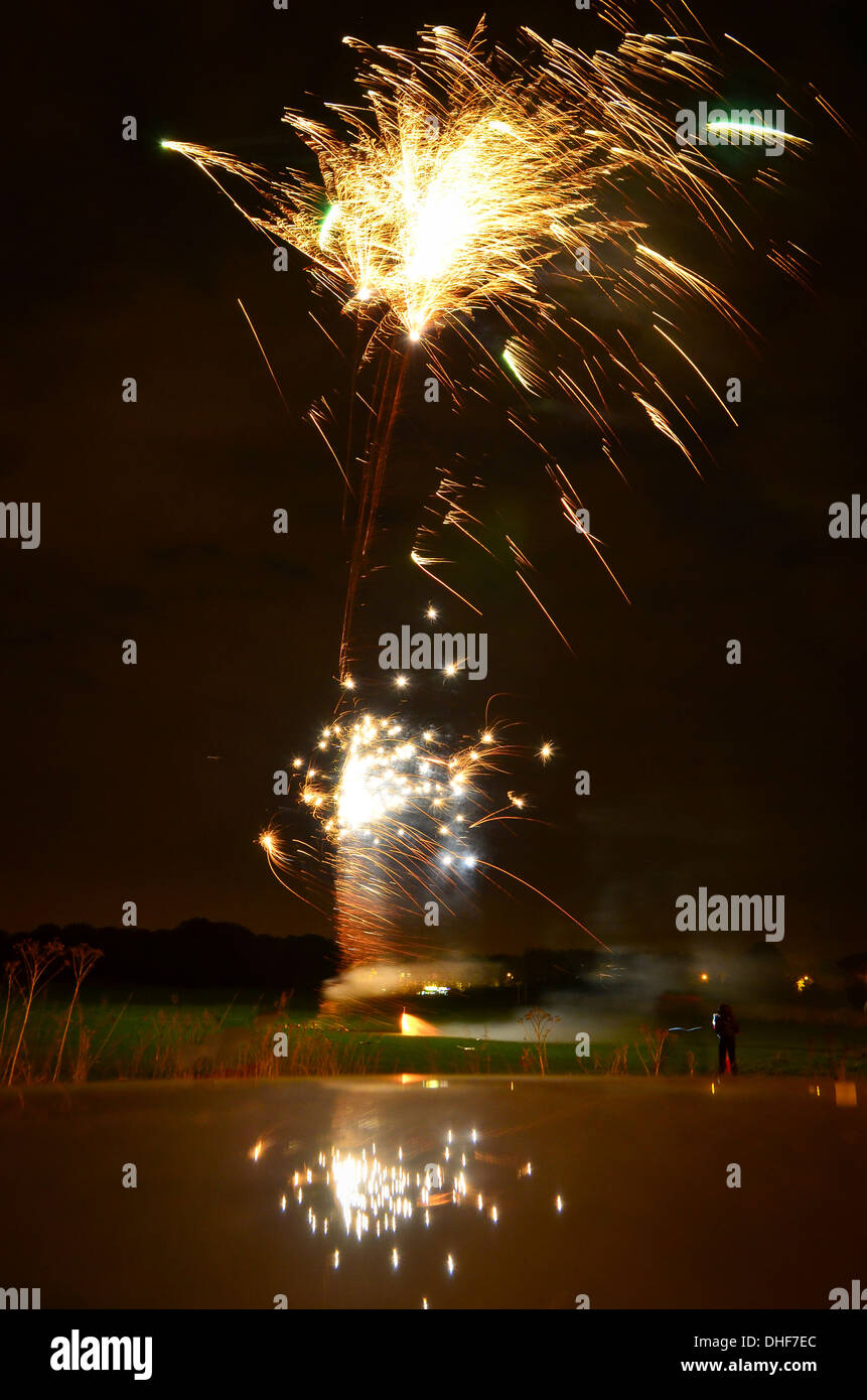 Fireworks exploding in the air on Guy Fawkes night reflected in the roof of a car Stock Photo