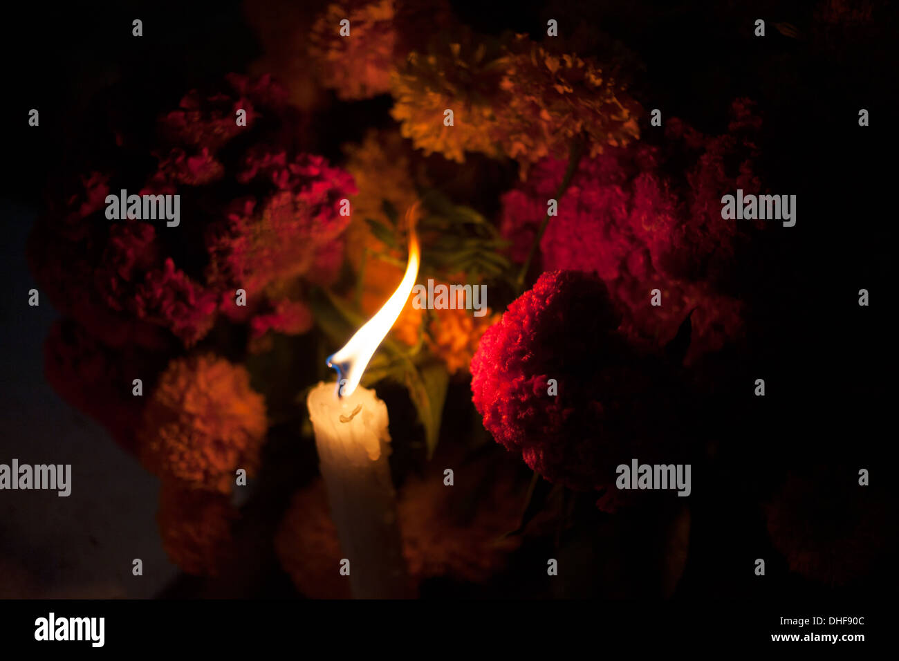 A candle and marigold flowers decorate a tomb during the Day of the