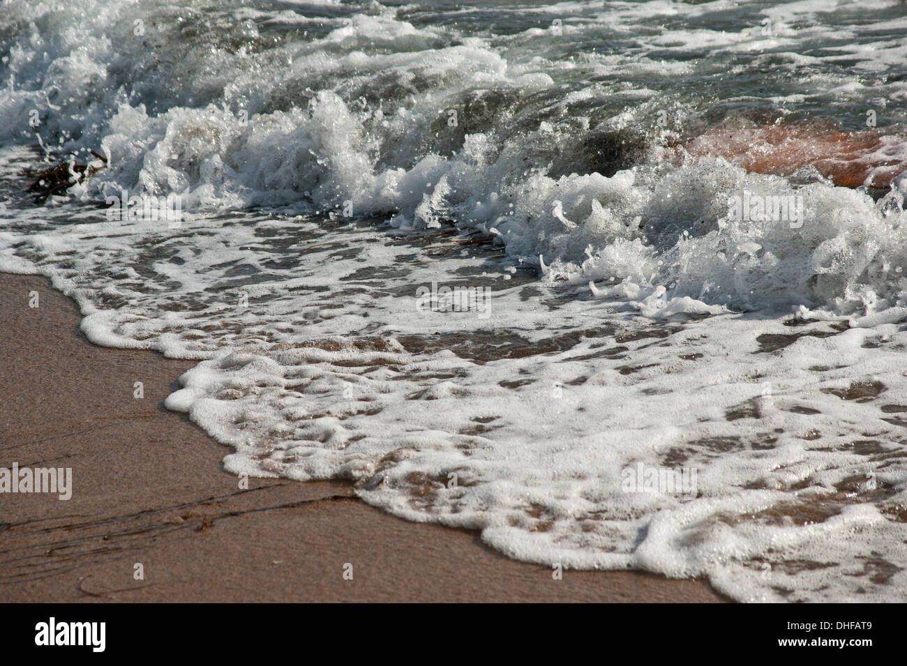 A wave breaking on the shoreline of a sandy beach Stock Photo