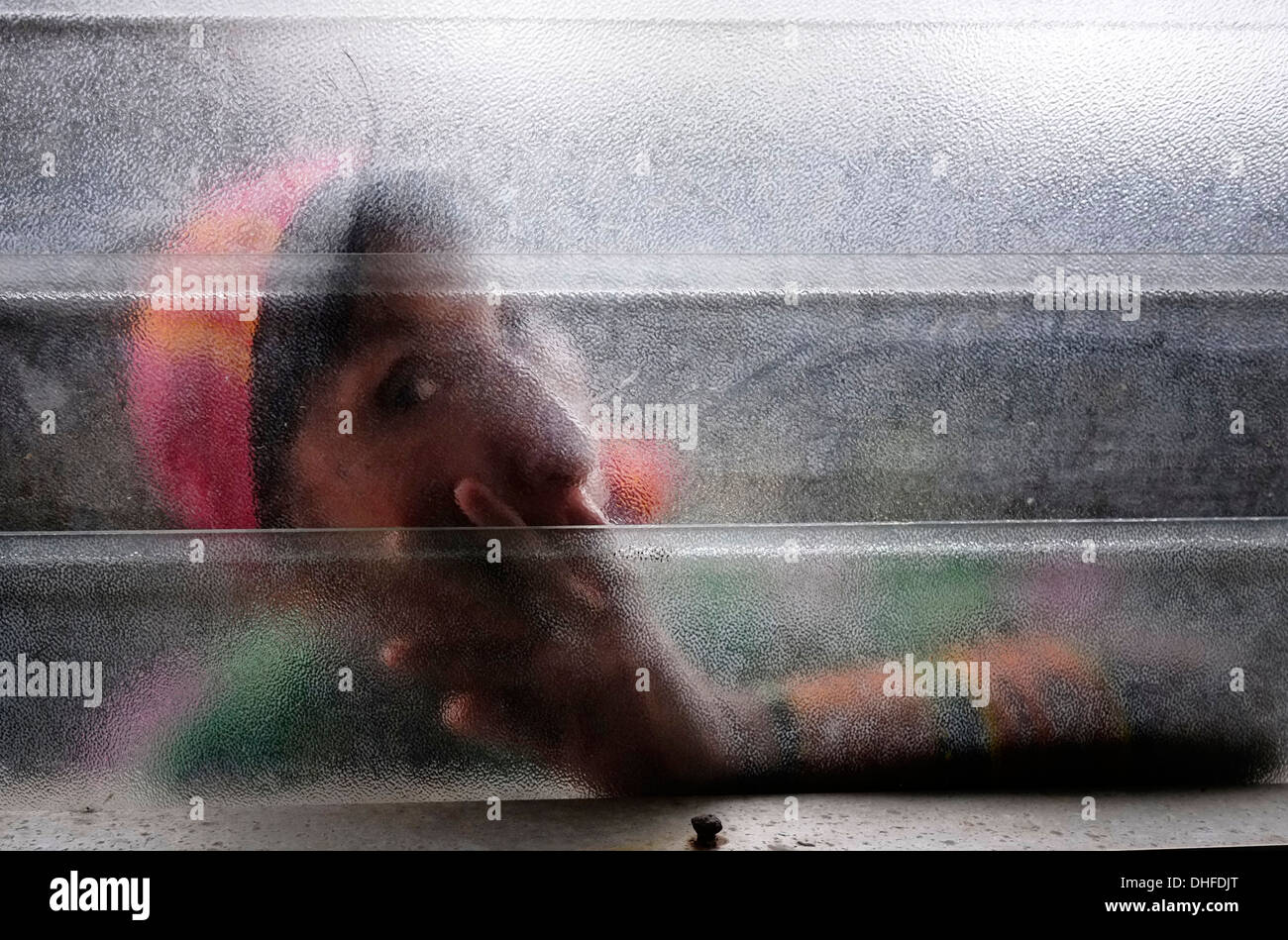 A woman from the Guna people is seen behind a glass window in Carti Sugtupu island village administered by Guna natives known as Kuna in the 'Comarca' (region) of the Guna Yala located in the archipelago of San Blas Blas islands in the Northeast of Panama facing the Caribbean Sea. Stock Photo