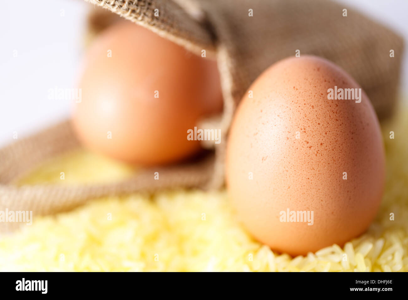 chicken egggs on yellow rice, in sack in the background Stock Photo