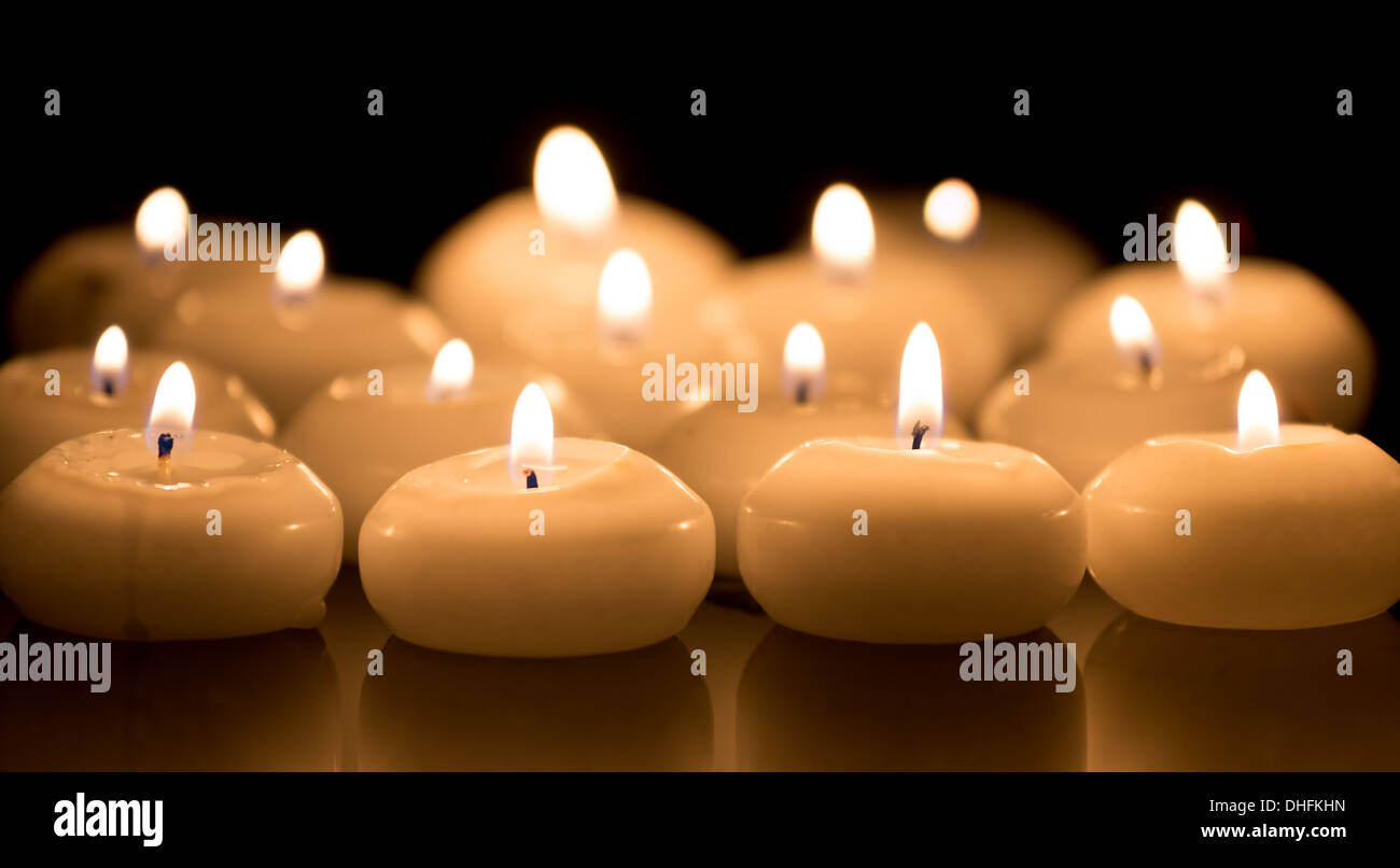 White candles on a black reflecting background Stock Photo
