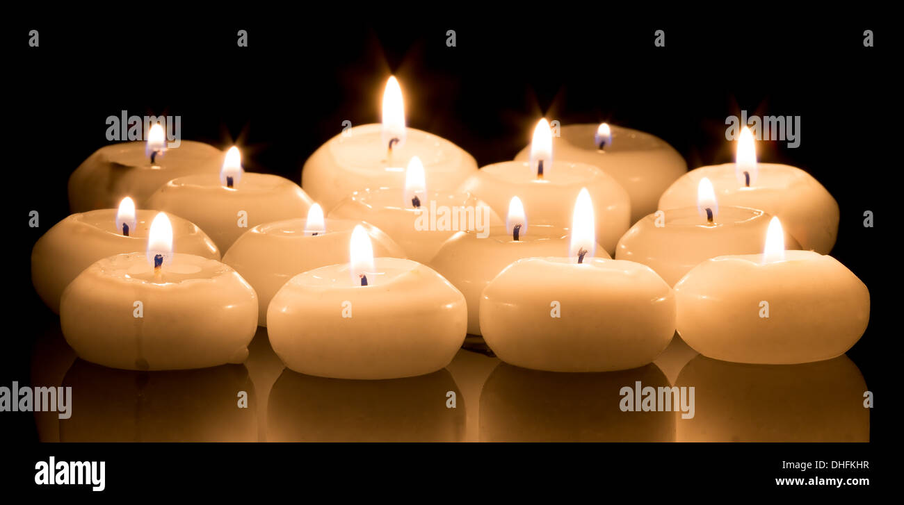 White candles on a black reflecting background Stock Photo
