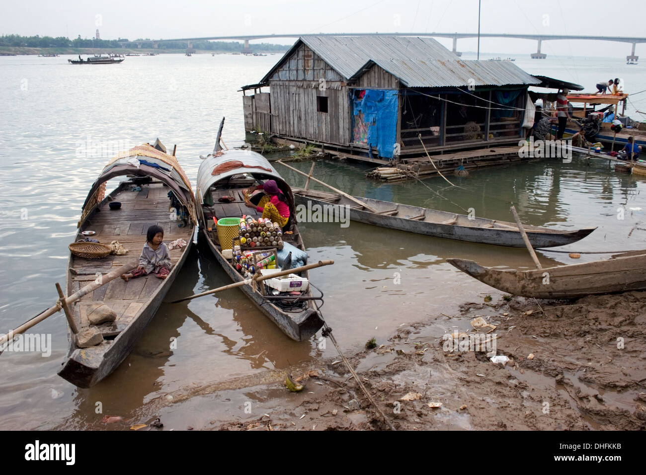 Wooden fishing boats are docked near a floating house at the shore of
