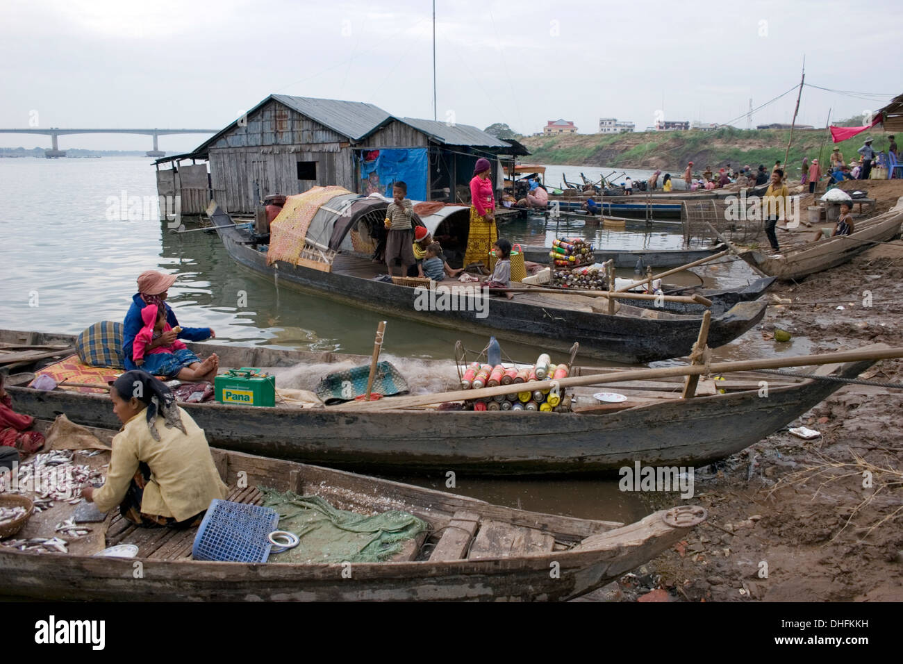 People are gathered on wooden fishing boats near a floating house at