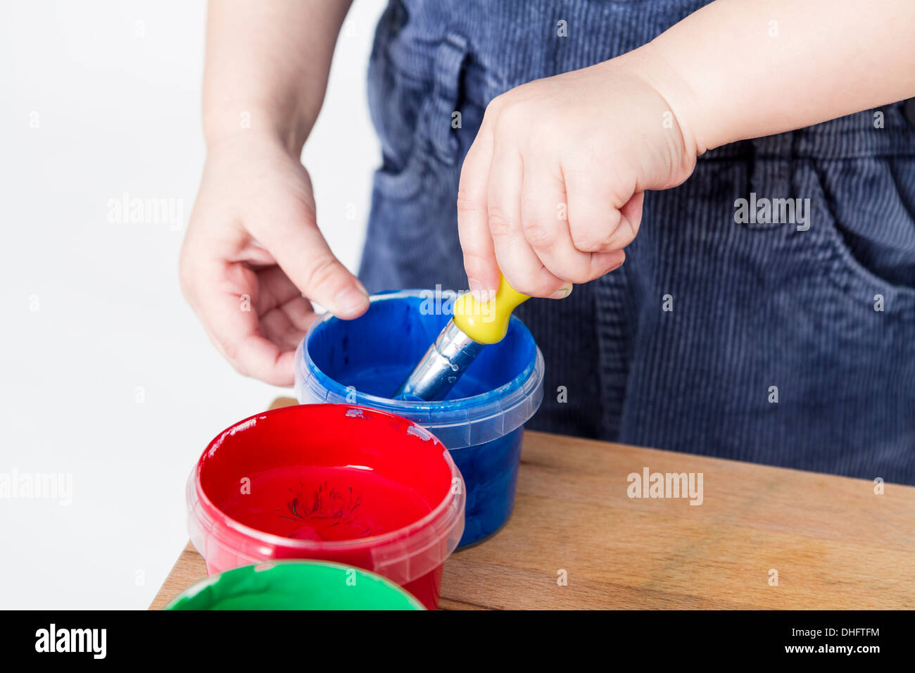 child holding brush in blue paint tub Stock Photo Alamy
