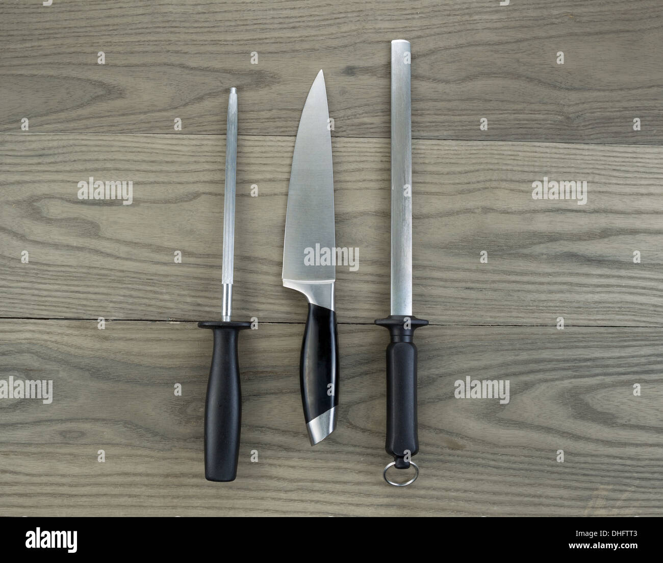 Photo of single large kitchen knife and two sharpeners on aged white ash wood Stock Photo