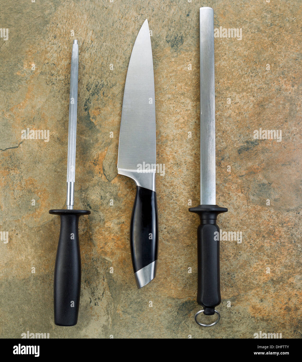 Photo of single large kitchen knife and two sharpeners on natural stone Stock Photo