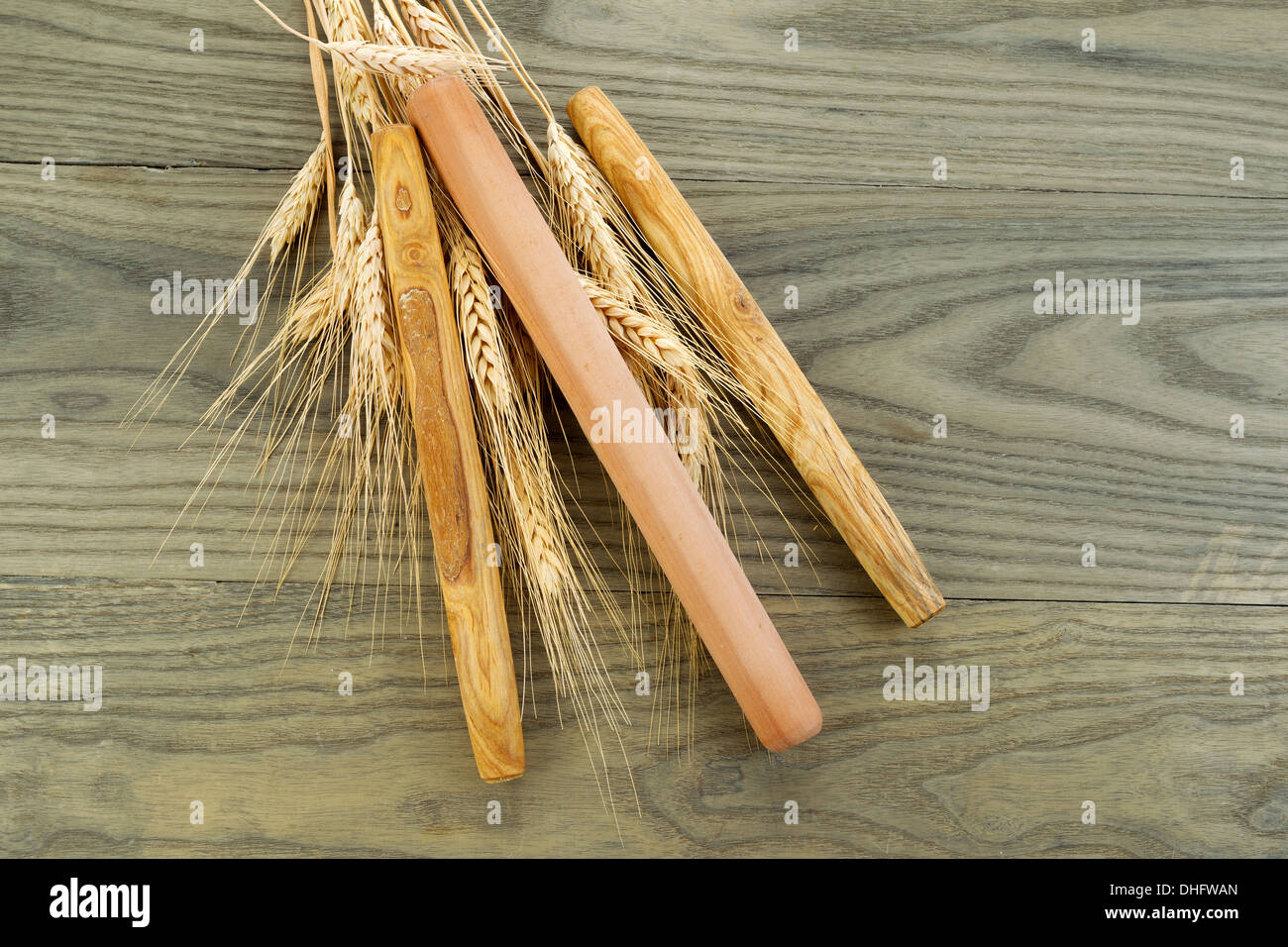 Horizontal photo of three wooden bread rollers on aged white ash wood boards with dried wheat stalks Stock Photo