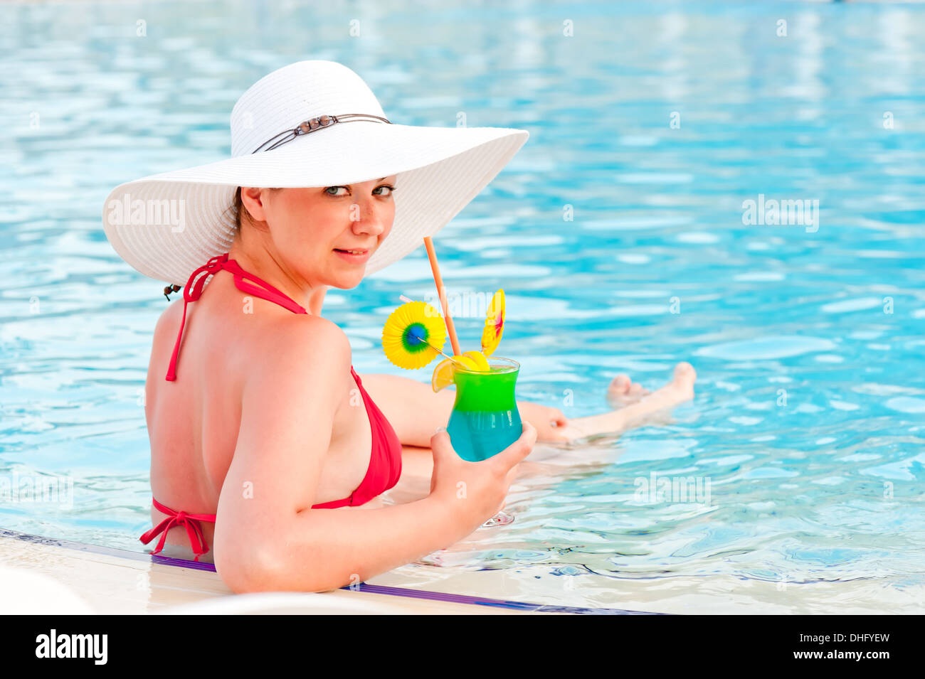 beautiful woman with a cocktail in the pool Stock Photo