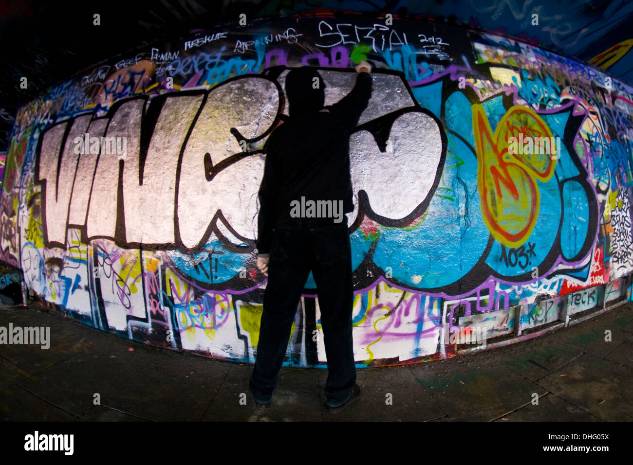 A graffiti artist sprays a wall Stock Photo - Alamy