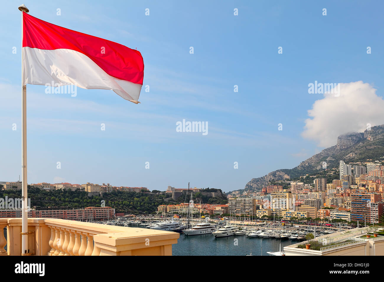 National flag, modern residential buildings and luxury yachts in Port Hercule under blue sky in Monte Carlo, Monaco. Stock Photo