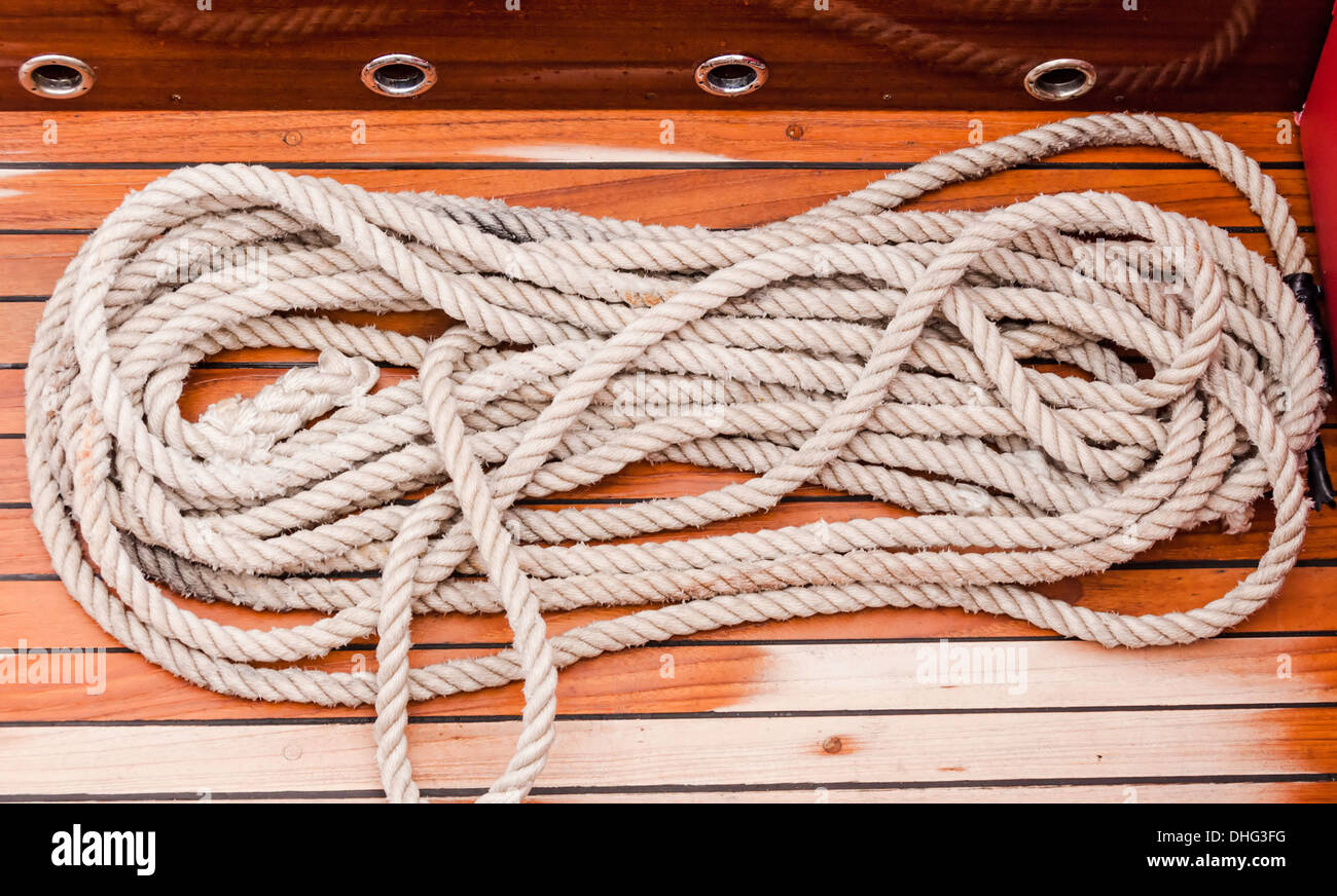 https://c8.alamy.com/comp/DHG3FG/marine-rope-coiled-on-a-wooden-dock-and-tied-to-a-metal-dock-cleat-DHG3FG.jpg