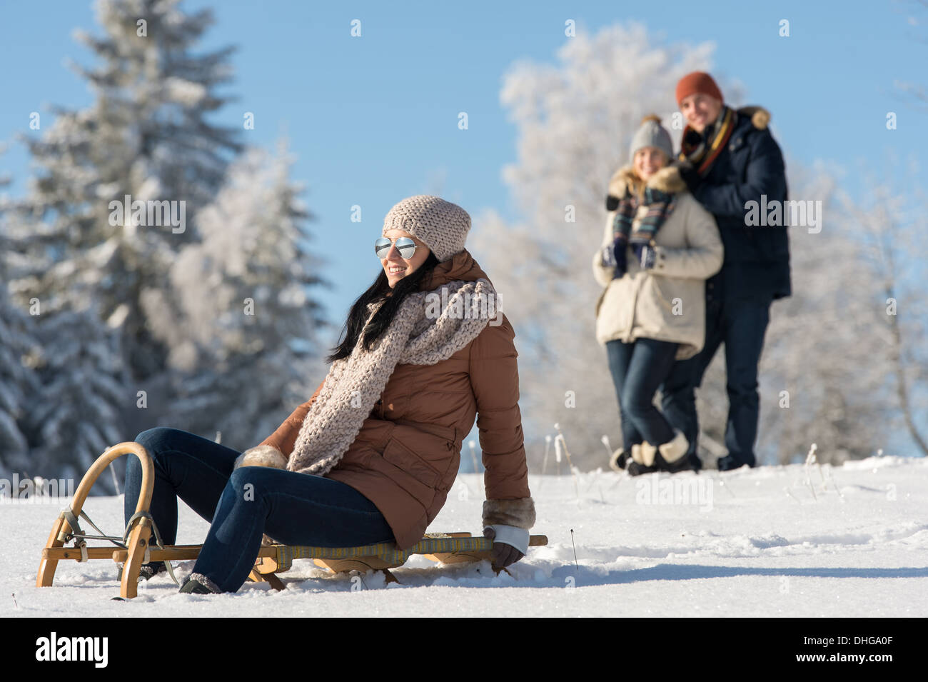 Friends enjoy sunny winter day on wooden sledge Stock Photo