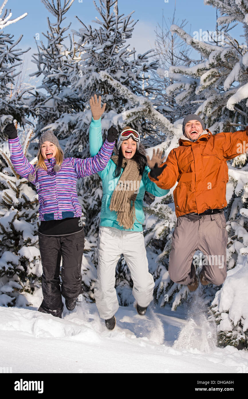Group of teenagers jumping together in wintertime snowy forest Stock Photo