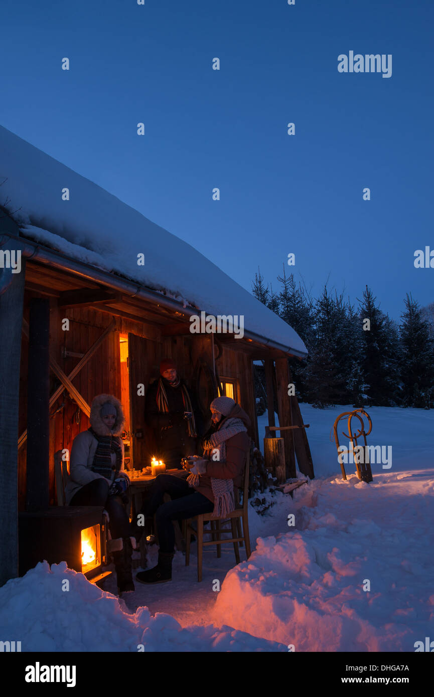 Sunset winter cottage friends enjoying evening in snow countryside Stock Photo