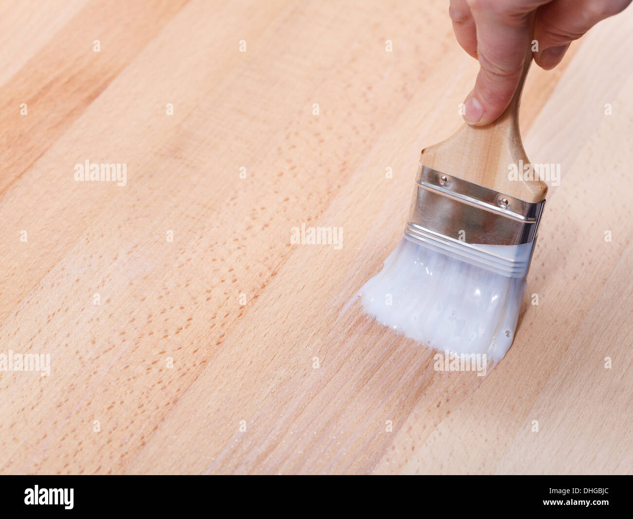 varnishing of surface of beech table top by paint brush Stock Photo