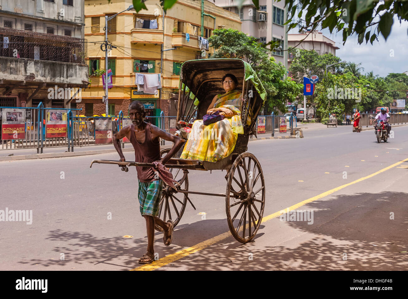 A man pulls a wooden rickshaw with passenger along a street on in Kolkata, India. Stock Photo