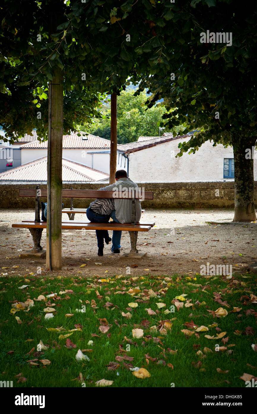 The back of a couple cuddling on a park bench in Autumn Stock Photo