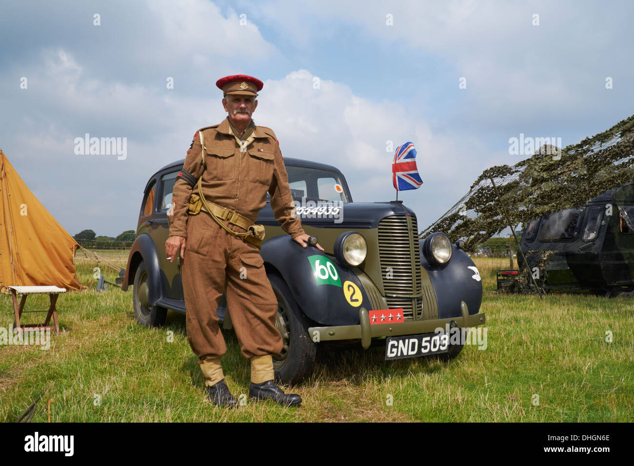 A man posing in WW2 British Army uniform by a 1942 Hillman Minx staff car. Rauceby War Weekend, Lincolnshire, England. Stock Photo